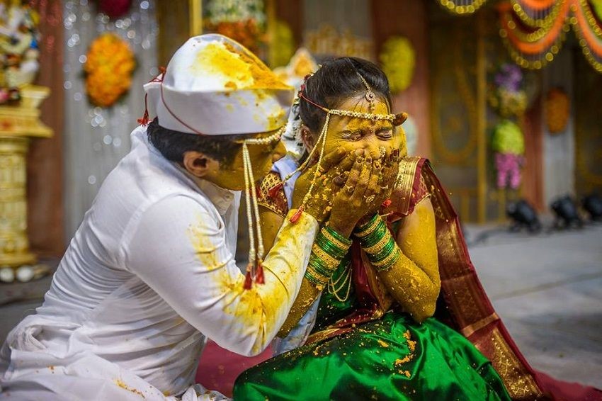 Candid shots of the couple during the Haldi ceremony, covered in turmeric paste, surrounded by laughter and fun.